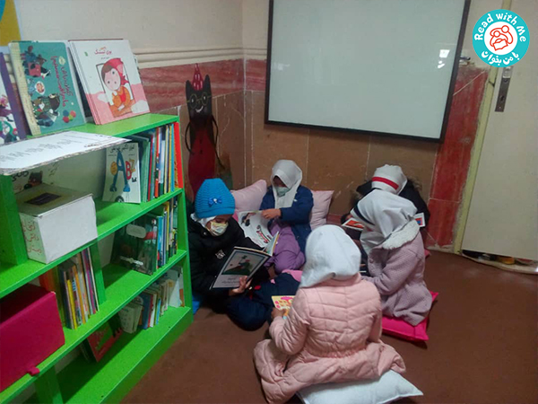 کودکان مشغول کتاب خواندن در کتابخانه با من بخوان